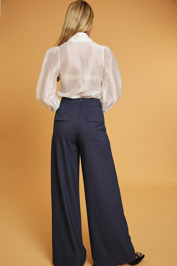 back view of model wearing denim blue High Waisted Wide Leg Dress Pants with a white button down blouse