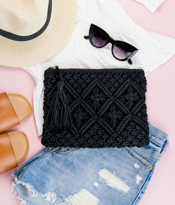 Black Woven Macrame Tassel Clutch flat lay with blue jean shorts, white top, hat and sunglasses
