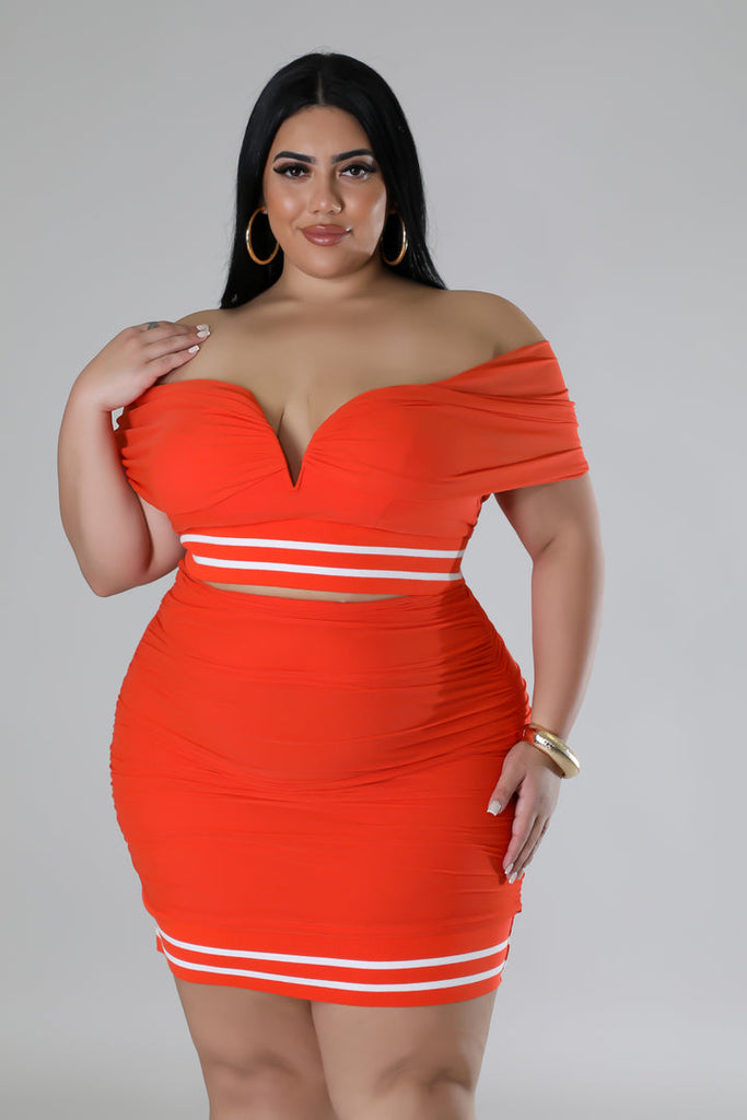 plus size model wearing orange plus size skirt set and gold jewelry