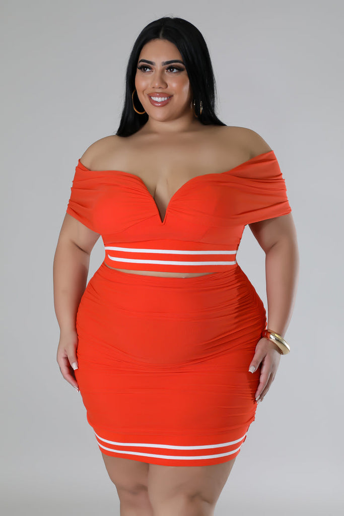 2X model smiling showcasing orange plus size skirt set