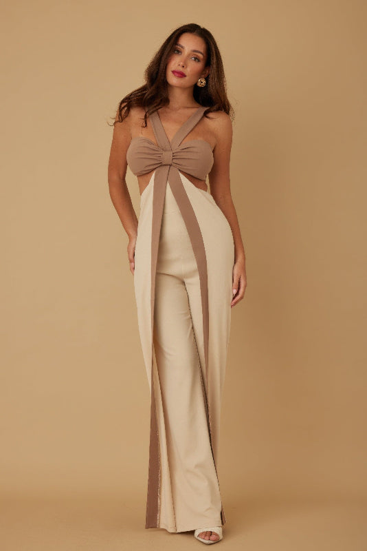 Woman wearing a beige and brown jumpsuit with a bow detail on a beige background