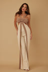 Woman wearing a beige and brown jumpsuit with a bow detail on a beige background