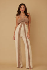 Woman wearing a beige and brown jumpsuit with a bow detail on a beige background