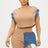 Woman wearing a beige top and denim shorts with a white background