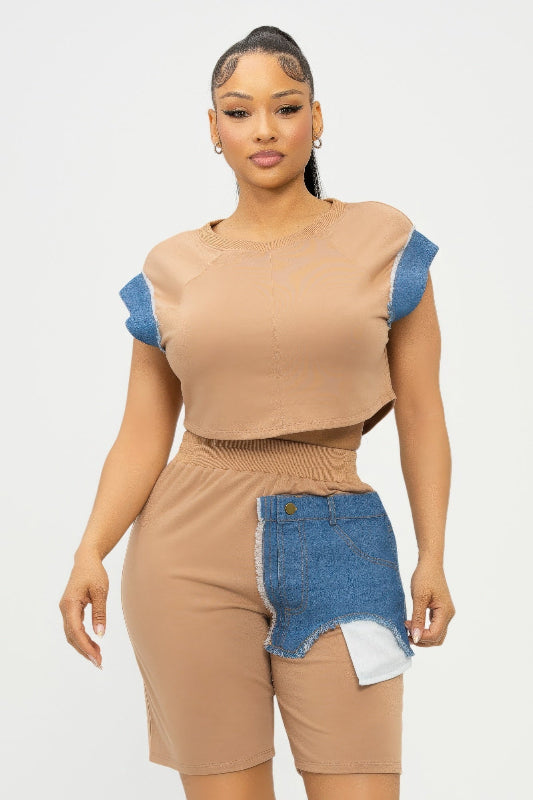 Woman wearing a beige top and denim shorts with a white background