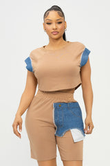 Woman wearing a beige top and denim shorts with a white background