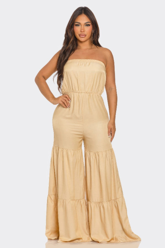 Woman wearing a beige strapless jumpsuit on a white background