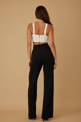 back view of a Woman wearing a black and white jumpsuit on a beige background