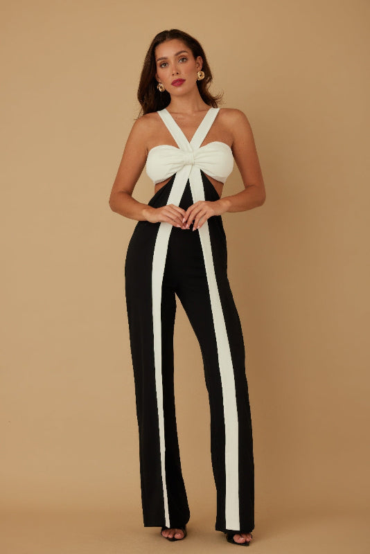 Woman wearing a black and white jumpsuit against a beige background