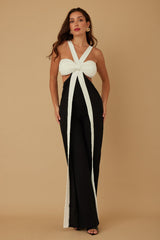 Woman wearing a black and white jumpsuit with a bow detail on a beige background