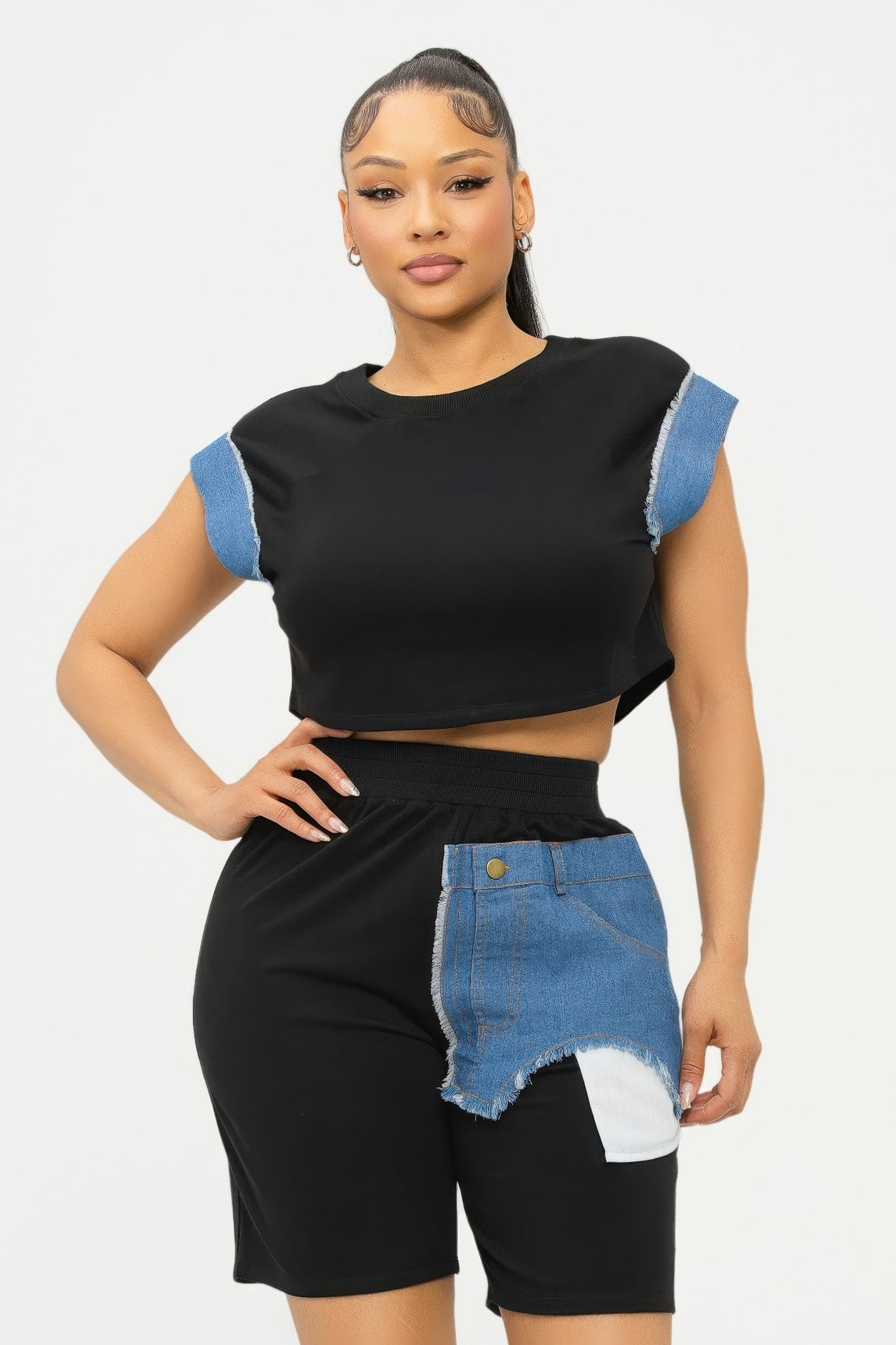 Woman wearing a black and denim outfit with a white background