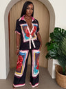 Woman wearing a colorful outfit with floral patterns in a room with a plant.