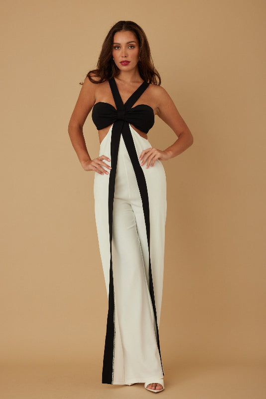 Woman wearing a black and white jumpsuit with a bow detail on a beige background