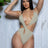 Woman wearing a beige swimsuit against a light wooden panel background
