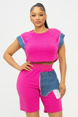 Woman wearing a bright pink short set with denim accents on a white background