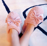 a model wearing a pair of pink fuzzy slippers on a dark colored marble floor