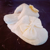 a pair of cream colored fuzzy slippers on a dark colored marble floor