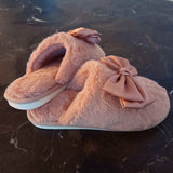 a pair of pink colored fuzzy slippers on a dark colored marble floor