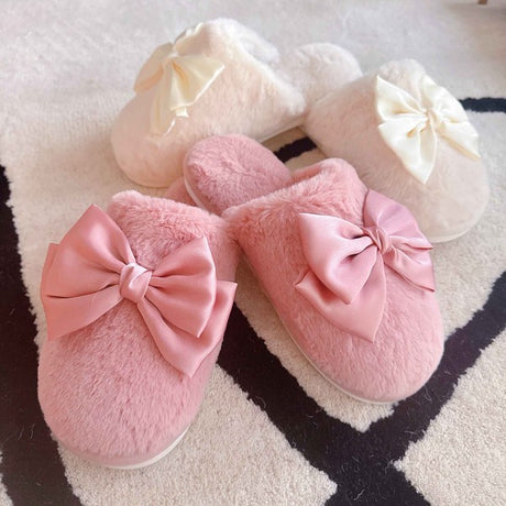 a pair of pink slide on slippers and a pair of cream color slide on slippers on a light colored rug