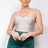 Woman wearing a silver bodysuit and green skirt against a plain background