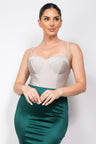 Woman wearing a silver bodysuit and green skirt against a plain background