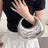 Person holding a silver handbag with a black top and white skirt.