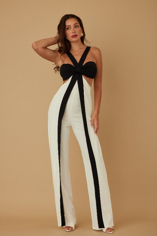 Woman wearing a black and white jumpsuit against a beige background