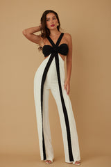 Woman wearing a black and white jumpsuit against a beige background