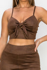 Top: A sleeveless crop top featuring an all-over embossed snake print, front tie, a sweetheart neckline, adjustable cami straps, and a square cut back.  Bottom: A pair of casual skinny leggings featuring an all-over embossed snake print, elasticized high-rise waistband, and a full length. 