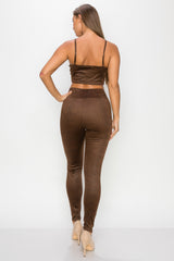 Top: A sleeveless crop top featuring an all-over embossed snake print, front tie, a sweetheart neckline, adjustable cami straps, and a square cut back.  Bottom: A pair of casual skinny leggings featuring an all-over embossed snake print, elasticized high-rise waistband, and a full length. 