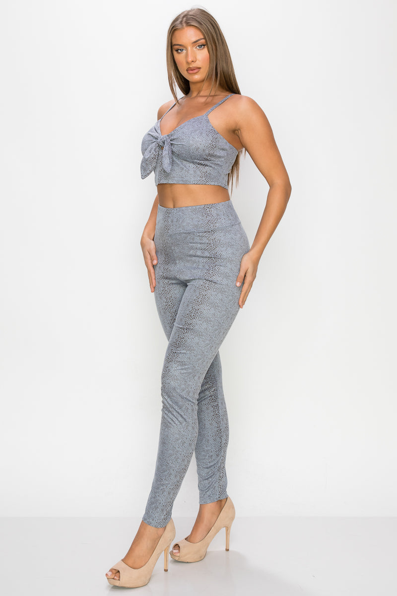 Top: A sleeveless crop top featuring an all-over embossed snake print, front tie, a sweetheart neckline, adjustable cami straps, and a square cut back.  Bottom: A pair of casual skinny leggings featuring an all-over embossed snake print, elasticized high-rise waistband, and a full length. 