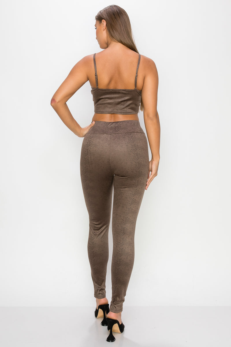 Top: A sleeveless crop top featuring an all-over embossed snake print, front tie, a sweetheart neckline, adjustable cami straps, and a square cut back.  Bottom: A pair of casual skinny leggings featuring an all-over embossed snake print, elasticized high-rise waistband, and a full length. 