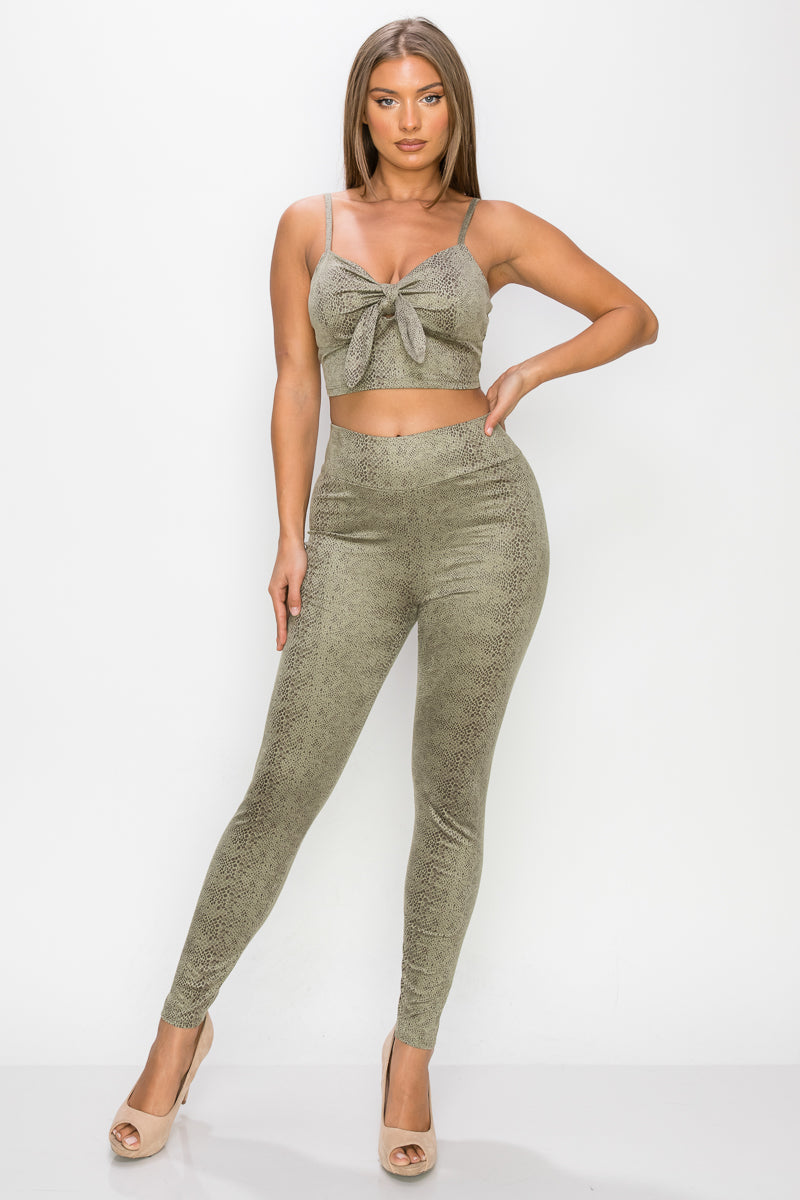 Top: A sleeveless crop top featuring an all-over embossed snake print, front tie, a sweetheart neckline, adjustable cami straps, and a square cut back.  Bottom: A pair of casual skinny leggings featuring an all-over embossed snake print, elasticized high-rise waistband, and a full length. 