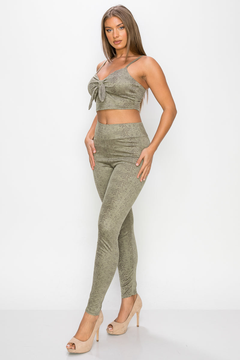 Top: A sleeveless crop top featuring an all-over embossed snake print, front tie, a sweetheart neckline, adjustable cami straps, and a square cut back.  Bottom: A pair of casual skinny leggings featuring an all-over embossed snake print, elasticized high-rise waistband, and a full length. 