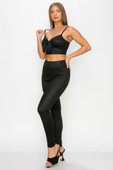 Top: A sleeveless crop top featuring an all-over embossed snake print, front tie, a sweetheart neckline, adjustable cami straps, and a square cut back.  Bottom: A pair of casual skinny leggings featuring an all-over embossed snake print, elasticized high-rise waistband, and a full length. 