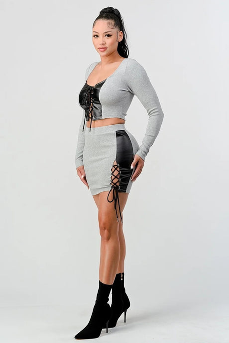 2 Piece Set with Cropped Long Sleeve Shirt with Pu Leather Detail and Crisscross Front Lace Up.  Matching Mini Skirt with Pu Leather Detail on Side with Crisscross Side Lace Up