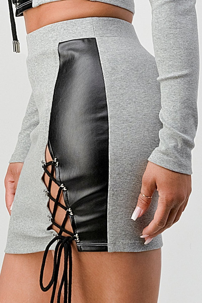 2 Piece Set with Cropped Long Sleeve Shirt with Pu Leather Detail and Crisscross Front Lace Up.  Matching Mini Skirt with Pu Leather Detail on Side with Crisscross Side Lace Up