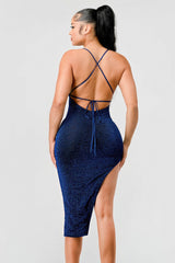 back view of model wearing royal blue metallic glitter side slit midi dress agains a white background